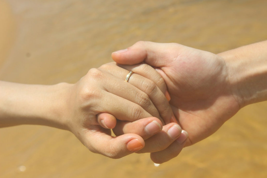 Two people holding hands, one supporting the other