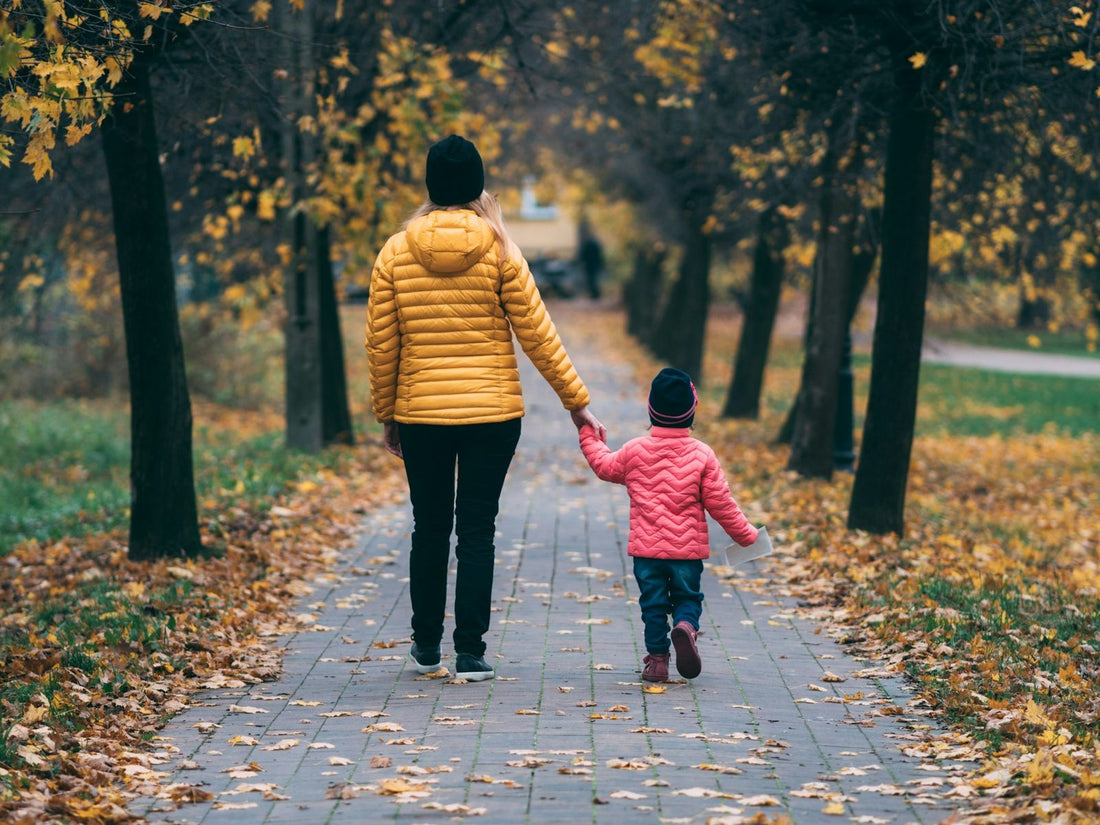 A mother walking through a park with her children